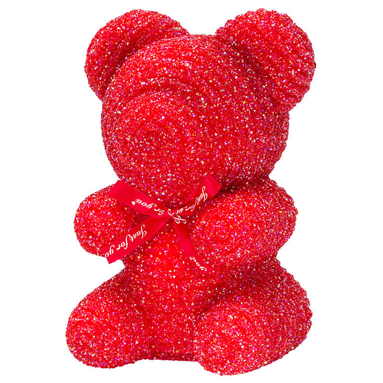 A decorative bear with red plastic glitter covered around the styrofoam bear.