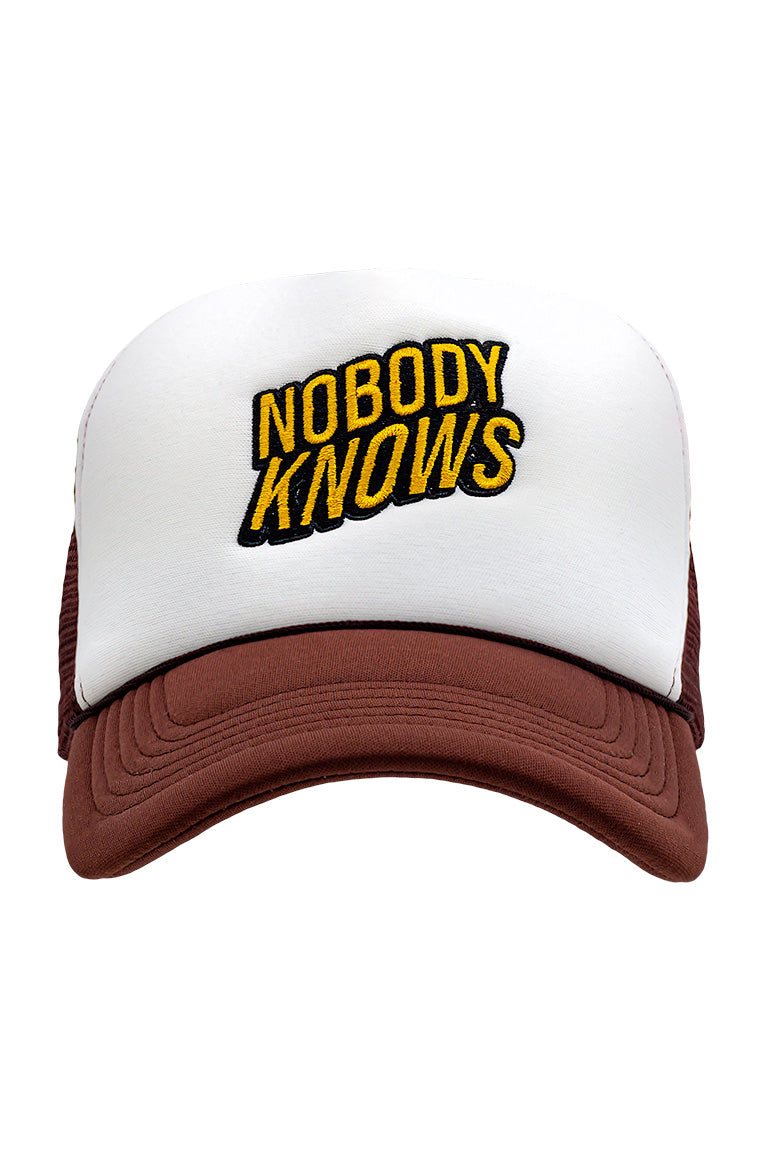 Front view of foam trucker hat with brown visor and white foam top. Breathable mesh in back of hat. Design on cap of black and yellow words saying "Nobody Knows"
