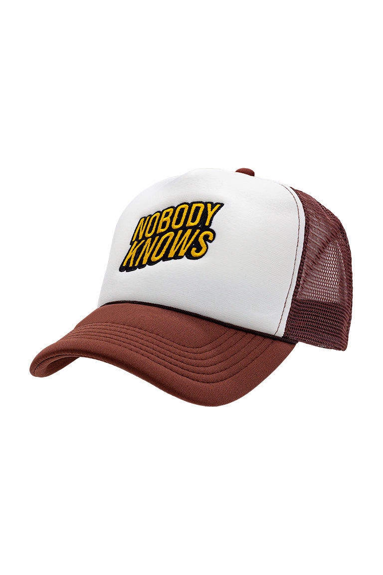 Side view of foam trucker hat with brown visor and white foam top. Breathable mesh in back of hat. Design on cap of black and yellow words saying "Nobody Knows"