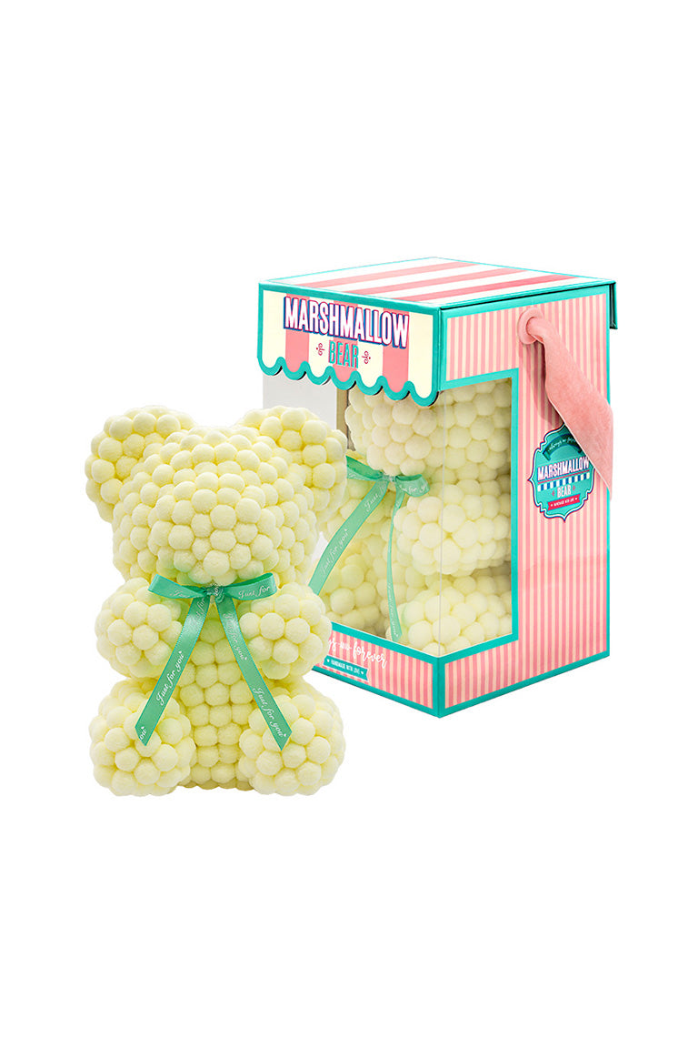 A yellow bear shape ornament covered in tiny foam balls with product packaging in the back