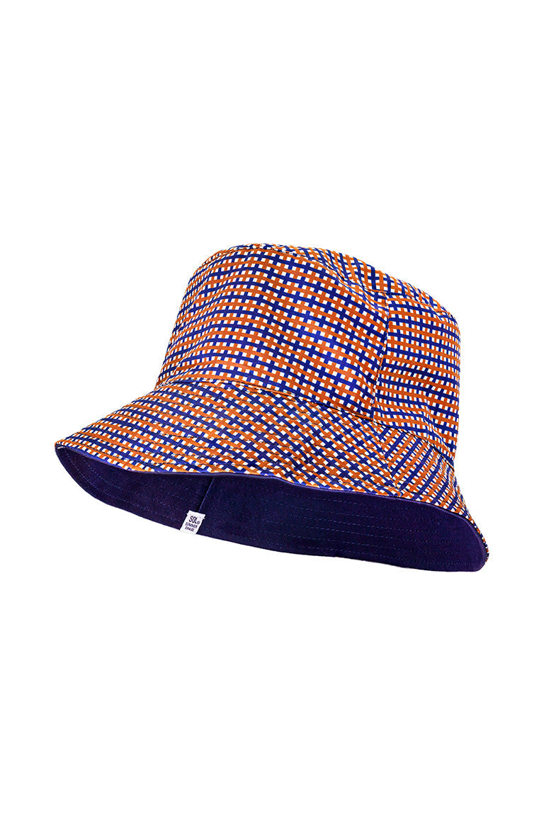 Side view of a reversible floppy bucket hat. With a plaid design and an all navy color inside.