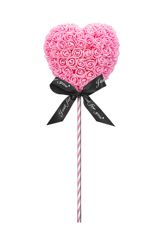 A heart shape lollipop looking decoration. Heart is pink cover in foam flowers. Attached with a red and white swirl stick with a black bow.