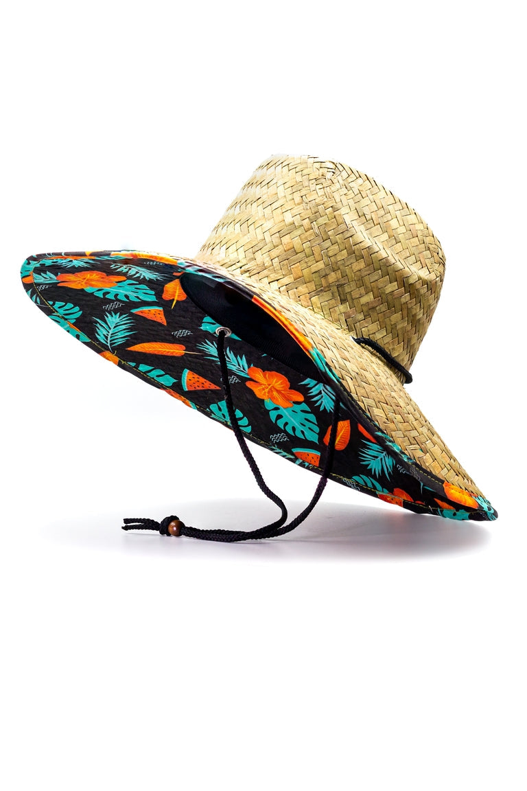 Side view of a straw hat with a tropical watermelon design pattern underneath the shaded visor with ablack chin strap