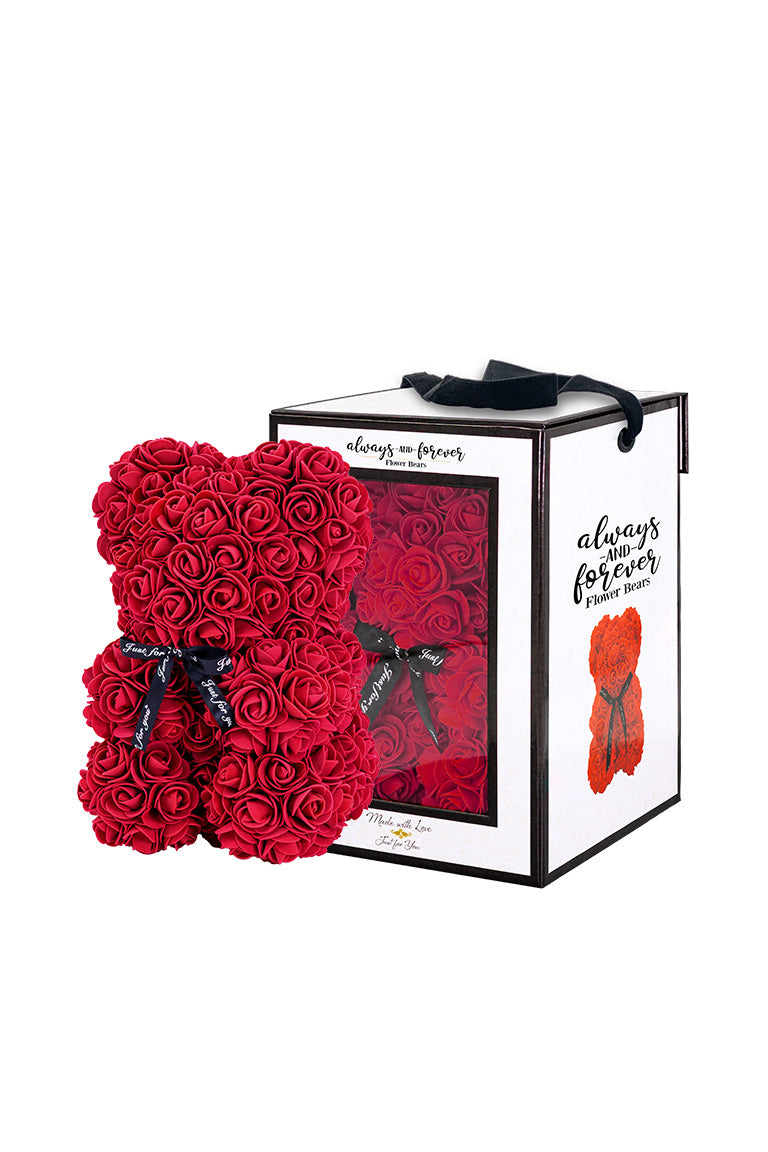 A bear shape decorative piece covered in burgundy foam flowers. With a black bow ribbon around underneath the head. Next to a white packaging box