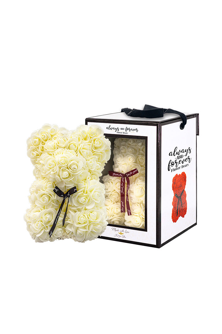 A bear shape decorative piece covered in cream color foam flowers. With a black bow ribbon around underneath the head. Next to a white packaging box