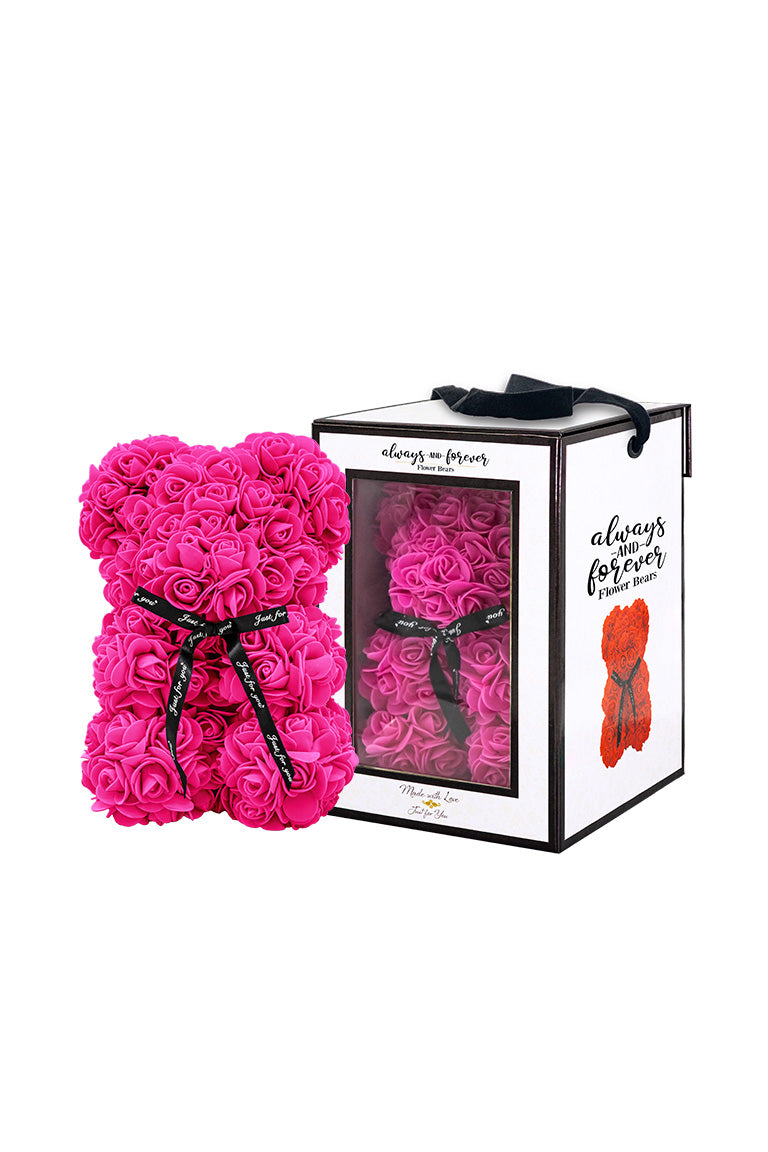 A bear shape decorative piece covered in rose color foam flowers. With a black bow ribbon around underneath the head. Next to a white packaging box
