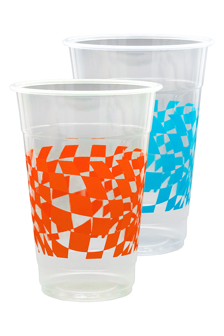 Close up of beer pong cups. 1 clear plastic cup with a orange checkered design and the other cup with a blue checkered design.