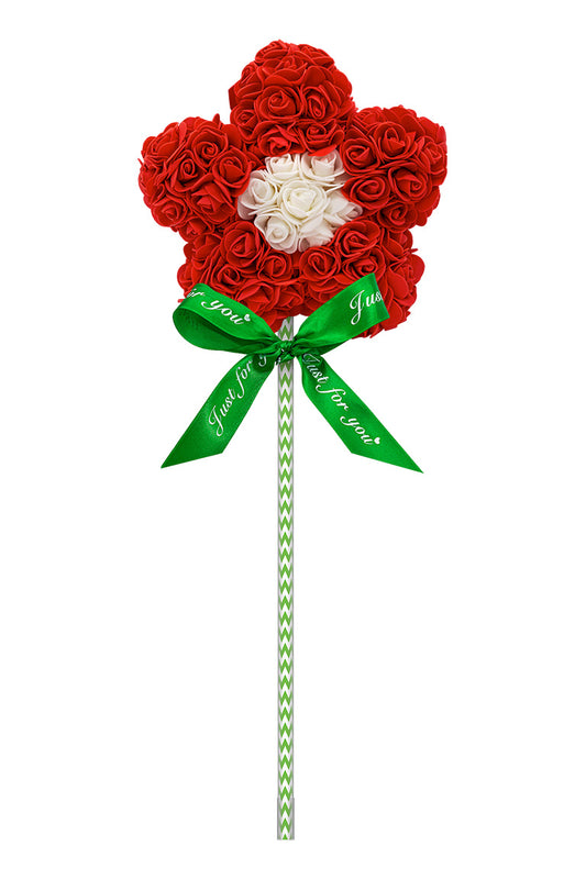 A flower shape lollipop looking decoration. Flower is red with a white center. Attached with a green and white swirl stick with a green bow.
